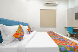 a bedroom with a white bed with colorful pillows at FabHotel Ramya in Indore