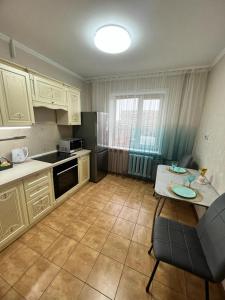 a kitchen with white cabinets and a table with a table at Квартира бизнес класса in Semey