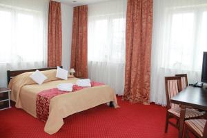 a bedroom with a bed with a red carpet at Hotel Kaprys in Świdnik