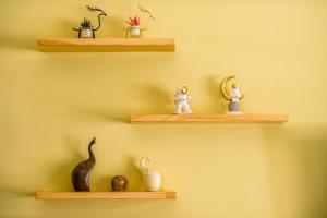 three shelves on a yellow wall with figurines on them at 綠舍睡到民宿 in Taitung City