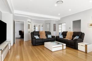 a living room with a black couch and a tv at Baudins of Busselton Bed and Breakfast - Adults only in Busselton