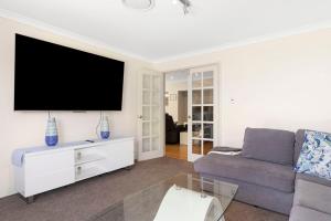 a living room with a couch and a flat screen tv at Baudins of Busselton Bed and Breakfast - Adults only in Busselton