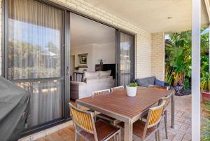 un patio con mesa de madera y sillas en Baudins of Busselton Bed and Breakfast - Adults only en Busselton