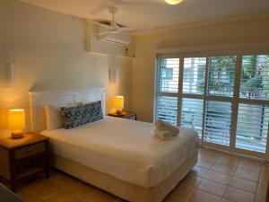 a bedroom with a white bed and a large window at The Cove Yamba in Yamba