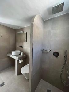 a bathroom with a shower and a toilet and a sink at Anna Maria Rooms Santorini in Perissa