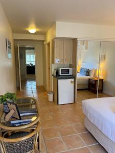 a room with a bed and a kitchen with a microwave at The Cove Yamba in Yamba