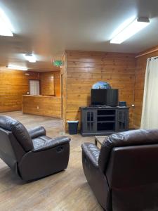 a living room with two leather couches and a television at Soldotna Lodge in Soldotna