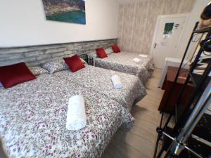 2 camas en una habitación de hotel con almohadas rojas en Pensión La Estación, en Logroño