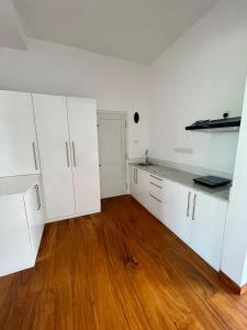 una cocina vacía con armarios blancos y suelo de madera en Atteriya HILLTOP en Matara