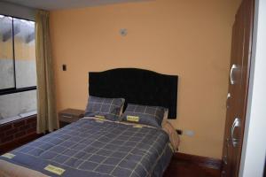 a bedroom with a bed with blue sheets and a window at Departamento excelente ubicación in Cusco