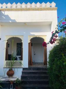 Jawai Leopard Villa في Bijāpur: منزل أبيض مع سلالم تؤدي إلى الباب الأمامي