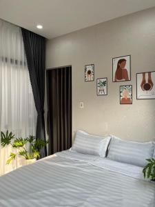 a white bed in a bedroom with pictures on the wall at LaLa Citadel Homestay in Hue