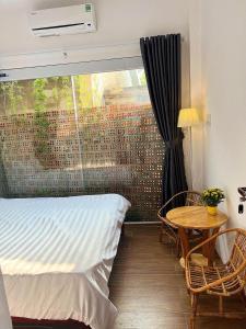 a bedroom with a bed and a table and a window at LaLa Citadel Homestay in Hue