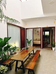 einen Holztisch und Bänke in einem Zimmer mit Pflanzen in der Unterkunft LaLa Citadel Homestay in Hue