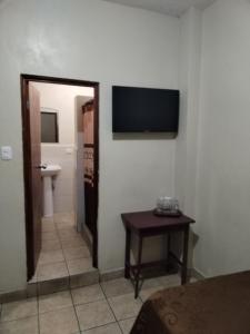 a bathroom with a toilet and a television on a wall at Hotel España in Guatemala