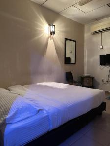 a bedroom with a large white bed with a light on the wall at G99 Hotel in George Town