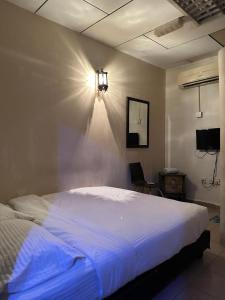a bedroom with a large white bed with a light on the wall at G99 Hotel in George Town