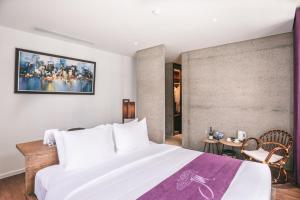 Un dormitorio con una gran cama blanca y una mesa en JM Boutique Hotel en Phu Quoc