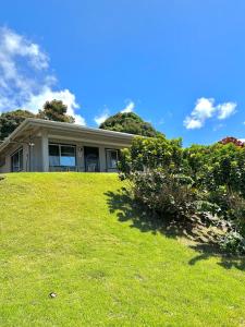 a house on top of a grassy hill at Kona Joe Coffee Farm in Kealakekua