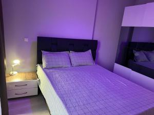 Dormitorio púrpura con cama con sábanas y almohadas púrpuras en Batışehir sitesi Mall of İstanbul, en Estambul