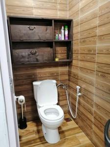 a bathroom with a toilet and a wooden wall at A+villa in Moka