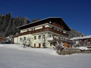 una grande casa nella neve con terreno ricoperto di neve di Gästehaus Hauser a Bach