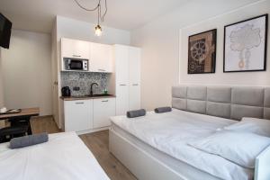 a bedroom with a large white bed and a kitchen at Dream Apartments - Gdańska 72 in Łódź