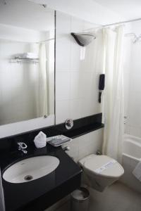 ein Badezimmer mit einem Waschbecken, einem WC und einem Spiegel in der Unterkunft Maurya Rajadhani in Thiruvananthapuram