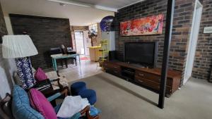a living room with a tv and a brick wall at Nature's Melody Share Home in Brisbane