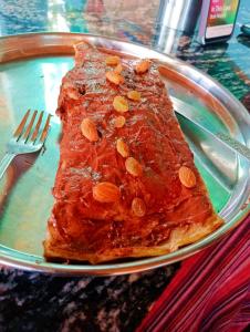 a piece of meat with almonds on a plate with a fork at Veera's Hostel in Pushkar