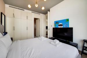 um quarto com uma cama branca e uma televisão de ecrã plano em Primestay - Index Tower, DIFC no Dubai