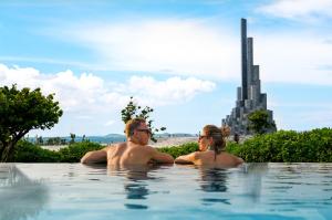 绥和市Stelia Beach Resort的坐在游泳池里的男人和女人