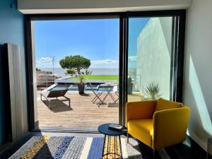 ein Wohnzimmer mit einem gelben Stuhl und einer Terrasse in der Unterkunft Villa Angoulins front de mer in Angoulins-sur-Mer