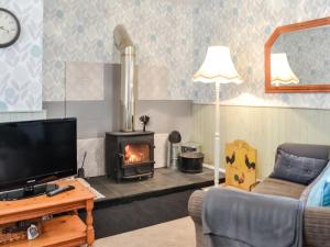 鄧弗里斯的住宿－Keepers Cottage，客厅设有壁炉和电视。