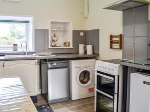 a kitchen with a washing machine and a sink at Keepers Cottage in Dumfries