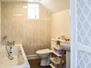 a bathroom with a tub and a toilet and a sink at Keepers Cottage in Dumfries