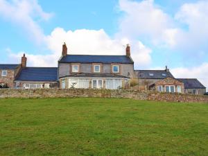 a large house with a stone wall and a grass field at The Old Farmhouse in Ancroft