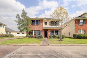 a brick house with a tree in front of a street at Houston Vacation Rental with Private Yard! in Houston