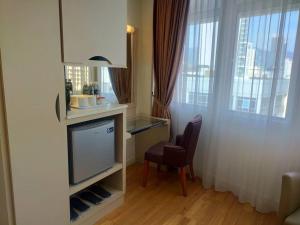 a room with a tv and a chair and a window at Hotel Sentral Georgetown @ City Centre in George Town