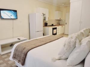 a bedroom with a large white bed with a tv on the wall at Hatfield Grosvenor Private Apartments in Pretoria