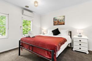 a bedroom with a bed with a red blanket at Kensington Escape - Balcony, BBQ and Parking in Melbourne