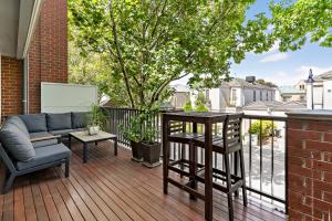 a patio with a couch and a table on a deck at Kensington Escape - Balcony, BBQ and Parking in Melbourne