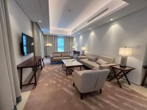 a living room with couches and chairs and a tv at Address Beach Resort Residence Fujairah in Fujairah