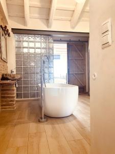 una gran bañera blanca en una habitación con ventana en El Nido: Una casita de ensueño, en Deltebre