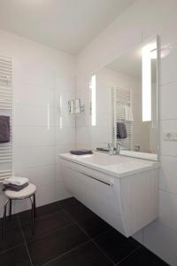 een witte badkamer met een wastafel en een spiegel bij Exquisit 3 in Norderney
