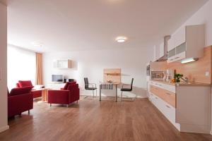 a kitchen and living room with red chairs and a table at Exquisit 3 in Norderney
