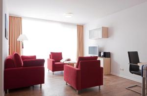 a living room with two red chairs and a television at Exquisit 3 in Norderney +5 photos