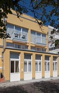 a yellow building with white doors and a balcony at Exquisit 3 in Norderney
