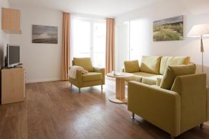 Una sala de estar con un sofá y sillas y un televisor. en Exquisit 4, en Norderney 5 fotos más