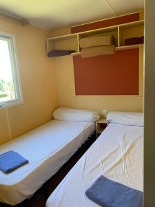 2 łóżka w małym pokoju z oknem w obiekcie Ernella w mieście Aléria